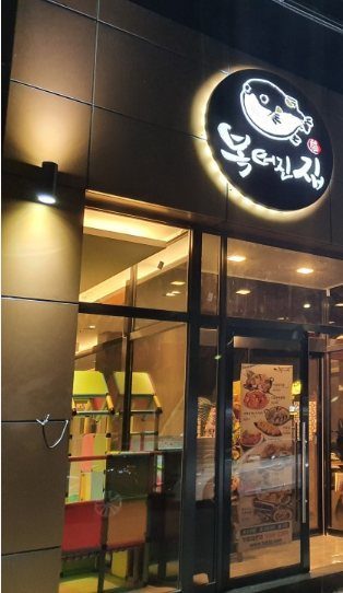 밤에 불을 밝힌 둥근 복어 그림 간판과 출입문